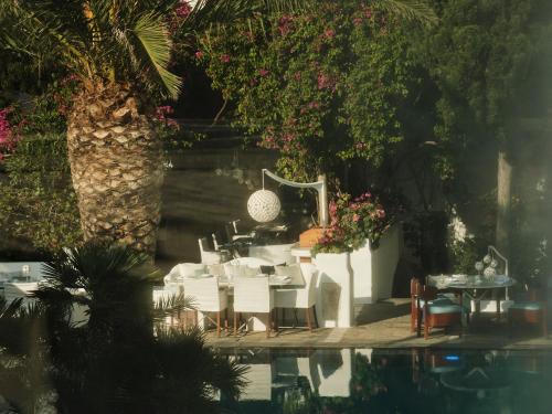 a restaurant with white tables and chairs next to a pool at Belvedere Mykonos - Main Hotel - The Leading Hotels of the World in Mýkonos City