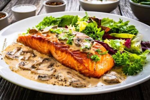 a white plate of food with fish and a salad at Sands Inn Hotel in Pwani Mchangani
