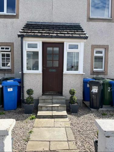 a house with a brown door and some trash cans at Two bedroom apartment Culloden Inverness Highlands in Culloden