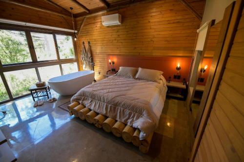 a bedroom with a large bed and a bath tub at Cabana Rústica em Gramado in Gramado