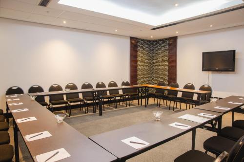 a conference room with tables and chairs and a screen at Premier Hotel East London ICC in East London
