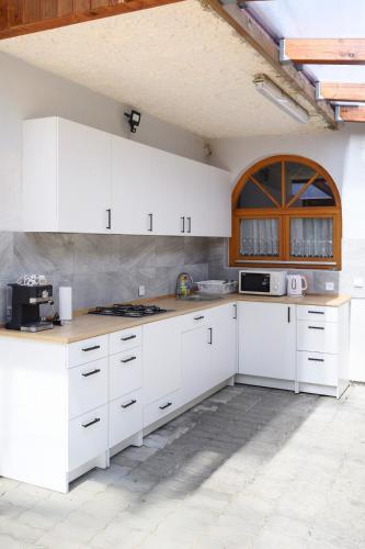 a white kitchen with white cabinets and a window at Molnár Apartman Zamárdi in Zamárdi