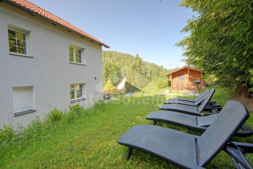 a row of chairs sitting in the grass next to a house at Ski/Bike Villa Sapporo ⃰ ⃰ ⃰ in Kraslice