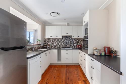 a kitchen with white cabinets and a wooden floor at 3-Bed Pet-Friendly Retreat Near Wentworth Falls in Wentworth Falls
