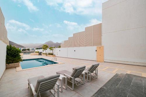 a patio with chairs and a swimming pool at Montagne 11 Luxury Villa 3 BR - Al Dana Island Fujairah in Fujairah
