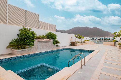 a swimming pool in front of a building with a mountain at Montagne 11 Luxury Villa 3 BR - Al Dana Island Fujairah in Fujairah