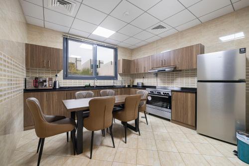 a kitchen with a table and chairs and a refrigerator at Montagne 11 Luxury Villa 3 BR - Al Dana Island Fujairah in Fujairah