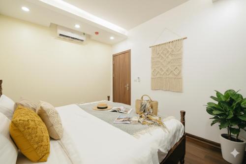 a bedroom with a large white bed with yellow pillows at Lunaria Two Bedroom Apartment - The Epicenter of Luxury and Convenience in Hanoi