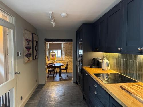 eine Küche mit marineblauen Schränken und ein Esszimmer in der Unterkunft Well Cottage, Thames St in Charlbury