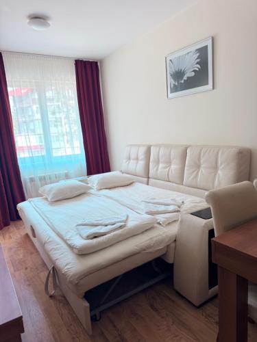 ein Schlafzimmer mit einem Bett und einer Couch und einem Fenster in der Unterkunft Prime location one bed apartment with hydro bath in Royal Plaza in Borowez