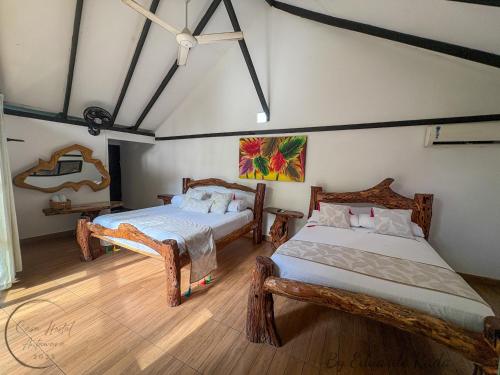 a bedroom with two beds and a painting on the wall at Hostal Antawara Tayrona in El Zaino