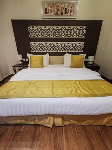 a bedroom with a large bed with yellow sheets at منازل بلقيس للشقق المخدومة فرع الشفاء in Hail