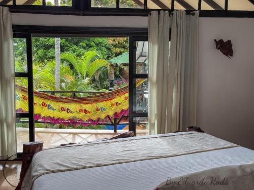 a bedroom with a bed and a large window at Hostal Antawara Tayrona in El Zaino