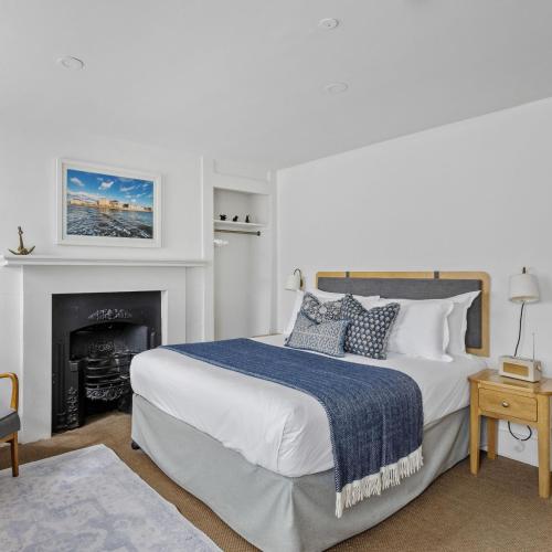 a white bedroom with a bed and a fireplace at Admiral's House by Maison Pierre in Plymouth