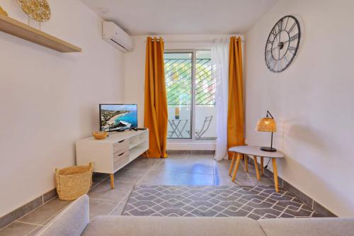 a living room with a couch and a clock on the wall at Le Studio Tanzantan in Saint-Paul