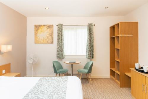 a hotel room with a bed and a table and chairs at Deangate Motel in Lydney