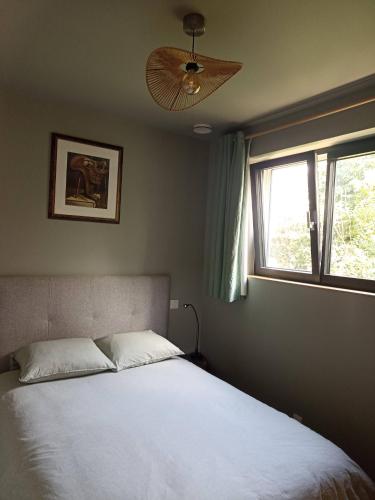 a bedroom with a bed with a fan and a window at Le petit Préau 10 min plages in Coudeville