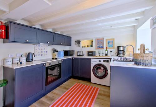 a kitchen with blue cabinets and a washing machine at Bluebell Cottage in Whitby