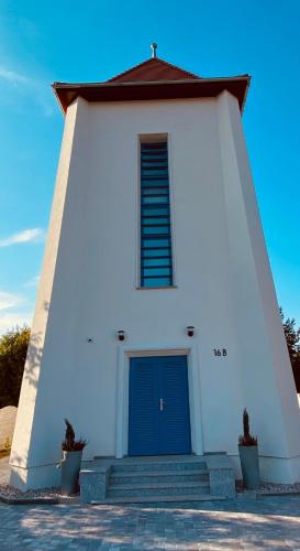 a small white church with a blue door at Wieża Ciśnień in Głuchołazy