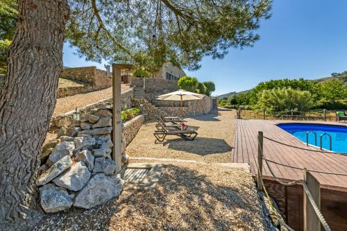 un patio con mesa y sombrilla junto a la piscina en Finca Wellnatura, en Artà