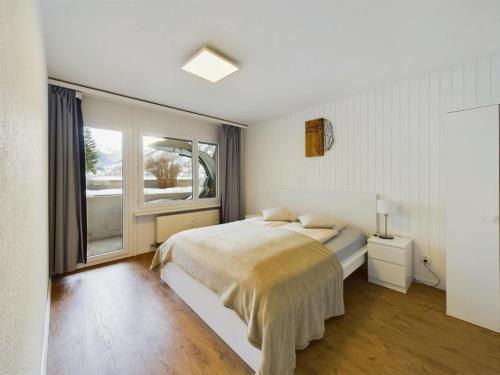 a white bedroom with a bed and a window at Alpine Retreat 4 Person Apartment near Zermatt with parking! in Täsch