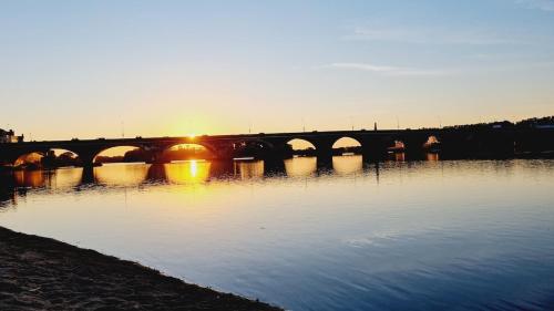 a bridge over a river with the sun setting at Maison avec jardin proche des bords de Loire in Les Ponts-de-Cé