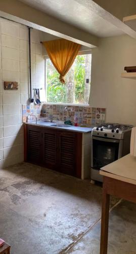 a kitchen with a stove and a window at Chalé - Praia in Ubatuba