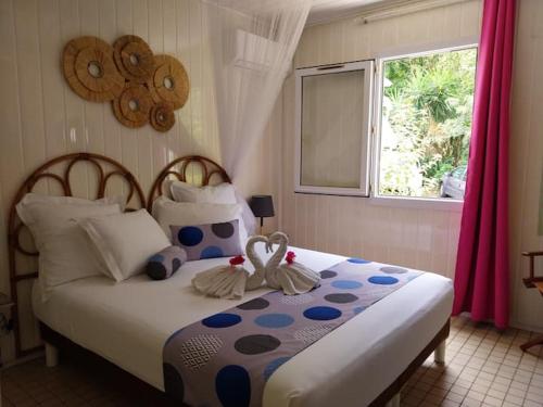 a bedroom with a bed with two swans on it at Résidence les hibiscus Les pieds dans l'eau in Bouillante
