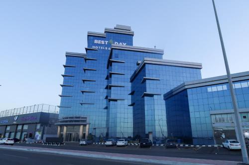 a large glass building with cars parked in a parking lot at Best Day Hotel and Resorts المحمدية in Jeddah