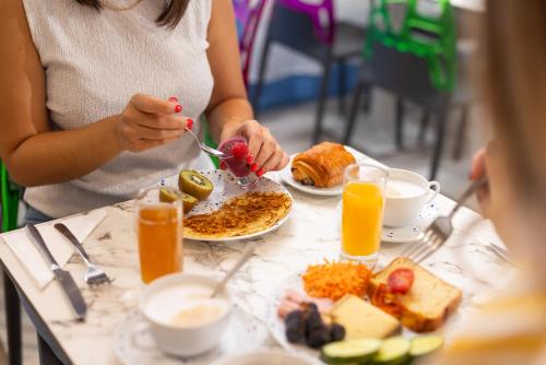 a woman sitting at a table with a plate of food at Hôtel Byakko Nice in Nice