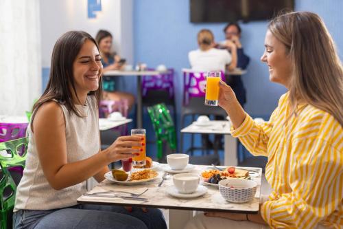 two women sitting at a table drinking orange juice at Hôtel Byakko Nice in Nice