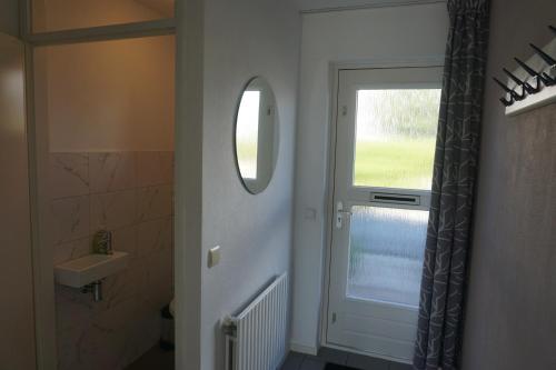 a bathroom with a door with a window and a sink at Kustverhuur, Vakantiepark Fort Soleil 26 in Breskens
