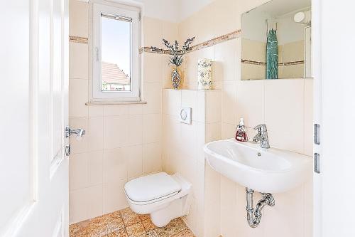 Un baño blanco con inodoro y lavabo. en Haus Seerose - Ferienhaus mit Garten nahe Fleesensee - Ruhe, Natur & Hund willkommen, en Göhren-Lebbin