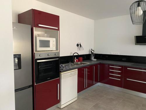 a kitchen with red cabinets and a microwave at Renovated house l Garden l Private parking in Arthès