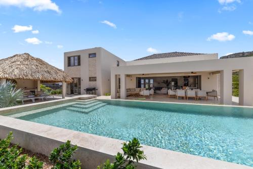 a villa with a swimming pool and a house at Blue Bay Curaçao Golf & Beach Resort in Willemstad