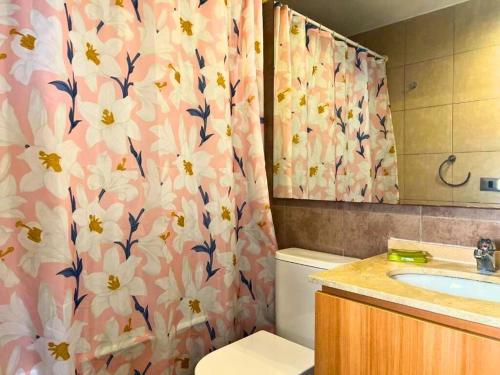 a bathroom with a toilet and a shower curtain with flowers at Hermoso departamento en Costa Horizonte in Concón
