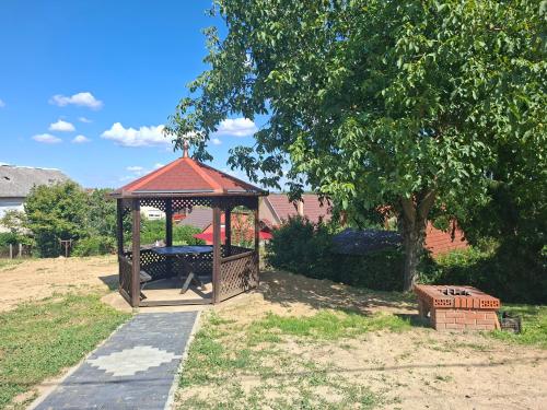 a gazebo in a yard with a tree at Gyöngyvirág Apartmanház in Zalakaros