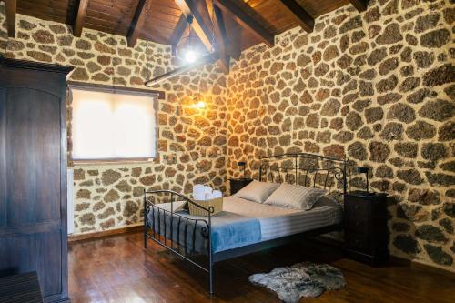 a bedroom with a bed in a stone wall at Filiantra Suites in Kato Trikala Korinthias