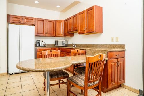 a kitchen with wooden cabinets and a table and chairs at Holiday Inn Express Hotel & Suites Barstow by IHG in Barstow