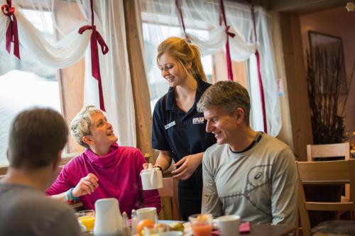 蒂涅Chalet Hotel L’Ecrin的一位女士站在一群桌旁的人旁边。