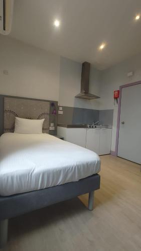 a bedroom with a large bed and a kitchen at London Croydon Hotel in Croydon
