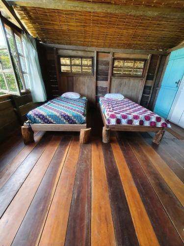 two beds in a room with wooden floors and windows at Casa Arco-Iris in Itacaré