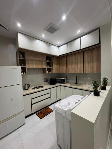 a kitchen with white appliances and wooden cabinets at دايموند جدة للشقق الفاخرة in Jeddah