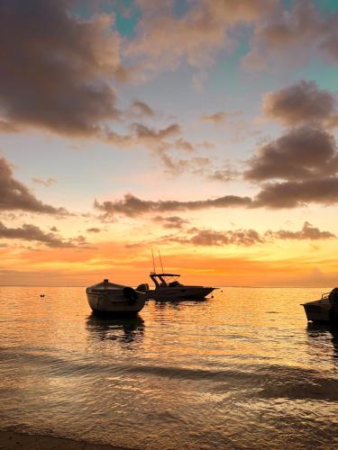 three boats sitting on the water at sunset at Searenity Villas in Rivière Noire
