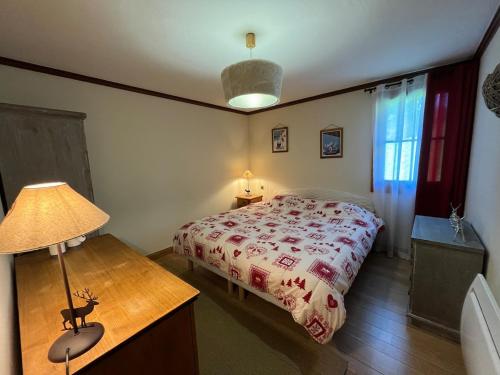 a bedroom with a bed and a table with a lamp at Appartement cosy avec jacuzzi privatif in Notre-Dame-de-Bellecombe