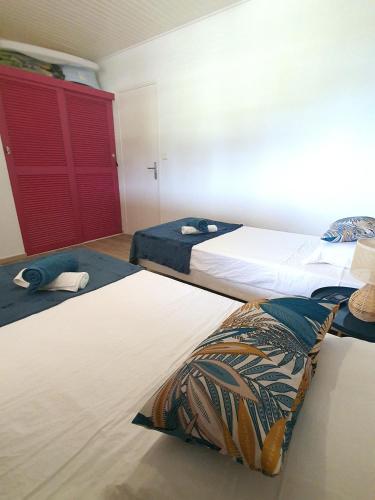 a bedroom with two beds and a red door at Kaza Maléssa in Sainte-Marie