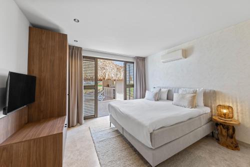 a bedroom with a large bed and a television at Blue Bay Curaçao Golf & Beach Resort in Willemstad