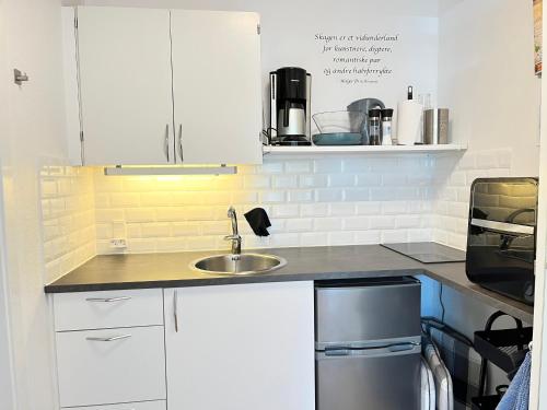 a kitchen with white cabinets and a sink at Eddies Bed & Breakfast in Skagen