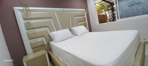 a white bed in a room with a window at Hotel y Cabañas Parinzzi in Guatapé