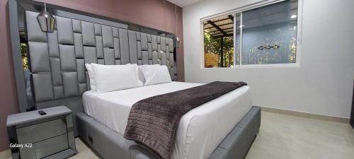 a bedroom with a large bed and a window at Hotel y Cabañas Parinzzi in Guatapé